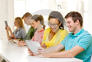 Smiling students looking at tablet pc at school