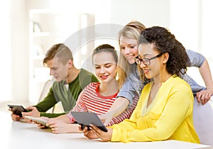 Smiling students looking at tablet pc at school