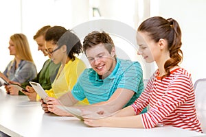 Smiling students looking at tablet pc at school