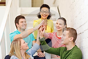 Smiling students making high five gesture sitting