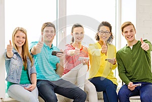 Smiling students with smartphone texting at school