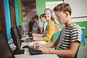 Smiling students studying in computer classroom