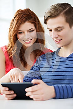 Smiling students with tablet pc at school