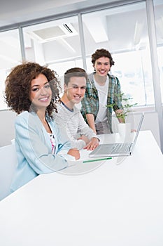 Smiling students working together on laptop