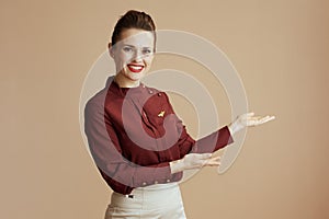 smiling stylish female air hostess on beige welcoming