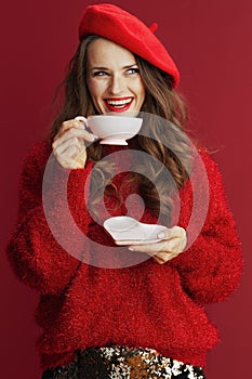 Smiling stylish female in red sweater and beret with tea cup