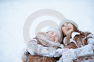 Smiling stylish mother and child laying in snow