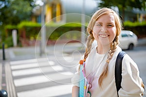 Smiling stylish pupil outdoors in city crossing crosswalk