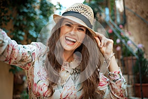 Smiling stylish tourist woman in old Europe town taking selfie