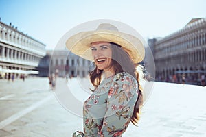 Smiling stylish traveller woman in floral dress with hat photo