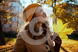 smiling stylish woman in beige coat and hat