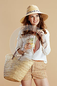 smiling stylish woman in blouse and shorts isolated on beige