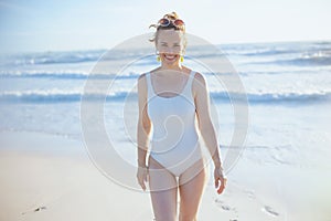 Smiling stylish woman in swimsuit at beach relaxing