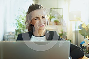 Smiling stylish woman using website while sitting on couch