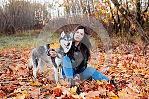 Smiling stylish woman walking with her husky in autumn day