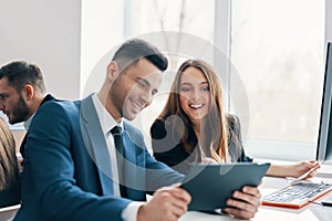 Smiling successful business people discussing ideas using digital tablet in office