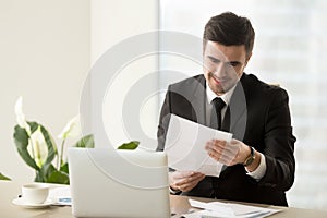 Smiling successful businessman holding document, reading good ne