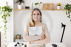 Smiling successful young businesswoman holding digital tablet posing in office