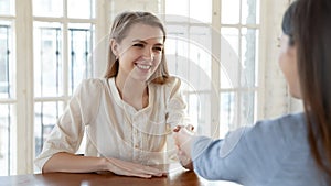 Smiling successful young woman candidate shaking recruiter employer hand
