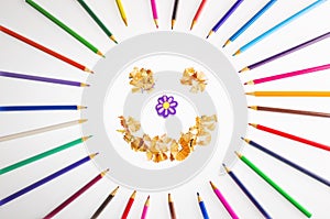 Smiling sun arranged from crayons and pencil sharpenings.