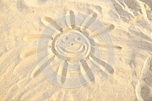 Smiling sun drawn in the sand