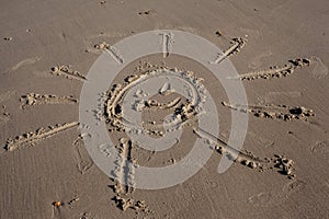 Smiling sun, drawn on the sand of a beach