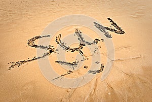 Smiling sun with inscription SUN on beach sand