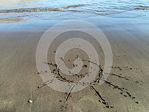 Smiling sun painted on the sand beach