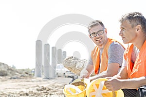 Smiling supervisor sitting with colleague at construction site