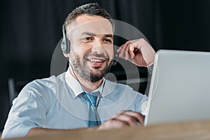 smiling support hotline worker with laptop and microphone