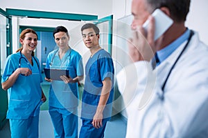 Smiling surgeons standing together with clipboard in corridor