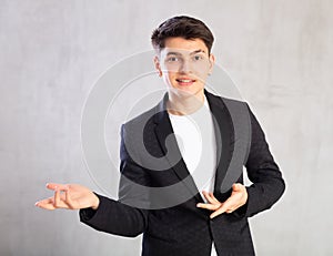 Smiling surprised young male student in suit jacket pointing at you.Portrait of guy pointing finger