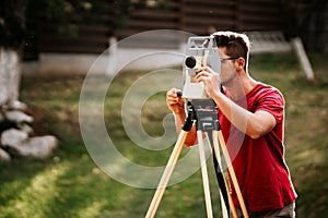 Smiling surveyor working with total station with coordinates, cartography industry details