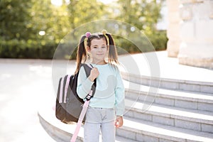 Smiling sweet happy little kid girl 5-6 year old wear casual clothes and backpack. Pupil child prepare for studying. Back to schoo