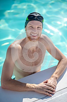 Smiling swimmer standing in water at edge of pool