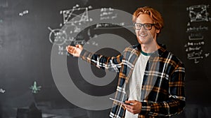 Smiling teacher point at blackboard with formulas
