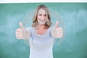 Smiling teacher standing thumbs up in front of blackboard