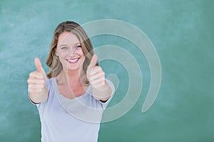 Smiling teacher standing thumbs up in front of blackboard