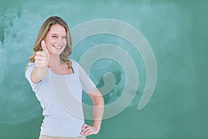 Smiling teacher standing thumbs up in front of blackboard