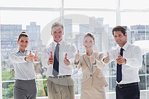 Smiling team of business people giving thumbs up