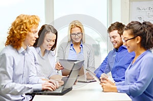 Smiling team with laptop and table pc computers