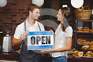 Smiling team posing with open sign