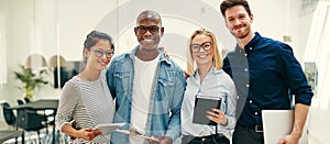 Smiling team of young businesspeople standing together in an office