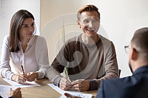 Smiling teammates discussing project with client at office.