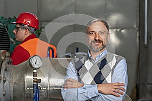 Smiling Technical Manager or Business Person Standing in Mechanical Room and Looking at Camera