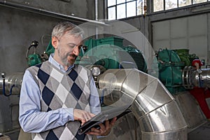 Smiling Technical Manager Using Digital Tablet in Mechanical Room