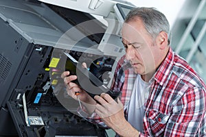 Smiling technician sitting near copier