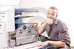 Smiling technician sitting near copier