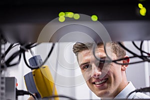 Smiling technician using digital cable analyzer on server