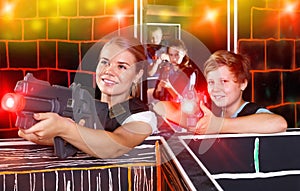 Smiling teen boy having fun on laser tag arena with his older si